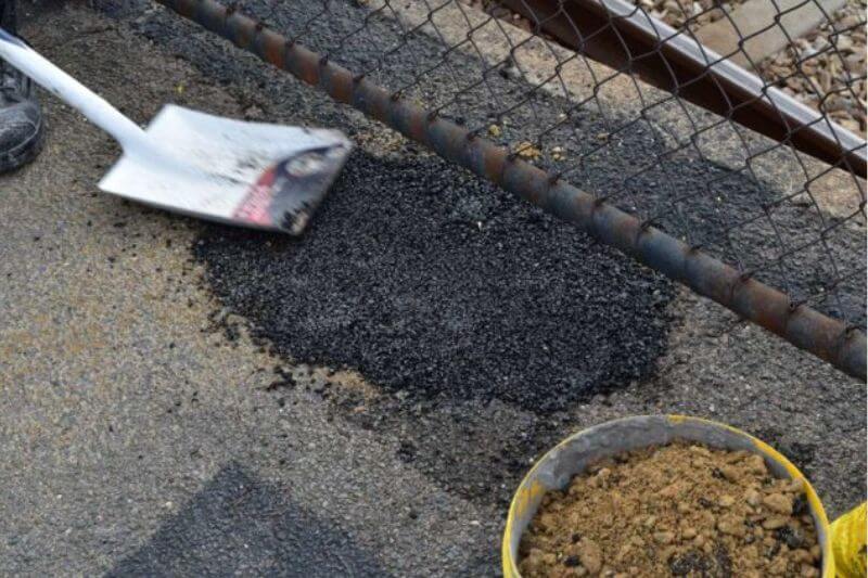 Spade pressing down on permanent asphalt repair