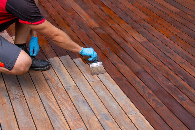 Worker hand applying liquid rubber decking solution to deck